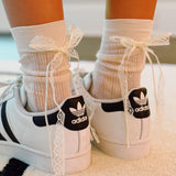 Set of two socks with lace detailing and satin bow accents at the back, offering a romantic and elegant touch to everyday looks.