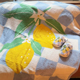 Soft blue and white checkered blanket featuring a charming leafy lemon design in vibrant yellow and green accents, perfect for adding a refreshing, cozy touch to any room.