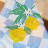 Soft blue and white checkered blanket featuring a charming leafy lemon design in vibrant yellow and green accents, perfect for adding a refreshing, cozy touch to any room.