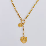 Gold-toned statement necklace featuring a bold chain and a cascading duo of engraved heart-shaped medallion pendants.