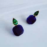 A pair of drop earrings featuring a uniquely sculpted irregular oval piece with a sparkle finish, topped by a small, contrasting accent element for added texture and elegance.