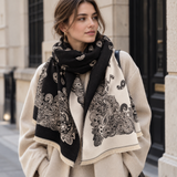 Model wearing Ellison+Young Luxe Bandana Paisley Shawl Scarf in Black Ivory wrapped at the neck over a cream coat