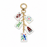 A gold-tone keychain charm featuring five miniature Mahjong-style playing card tiles: a red 2, green 3, pink flower, red pagoda with 'JOKER' text, and a blue bird on a branch. The keychain is photographed on a clean white background.