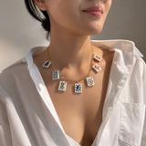 Necklace with card-themed pendants worn by a person in a white shirt.