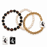 Three beaded stretch bracelets arranged on a white background, with two black-and-gold marbled bracelets, one cream pearl bracelet, and two square white tiles showing koi fish designs labeled Side A and Side B.
