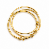 Three gold bangles stacked on a white background