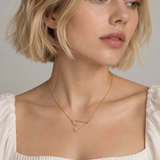 Model wearing the gold Modern Open Heart Pendant Necklace sideways with a white puff-sleeve square-neck top