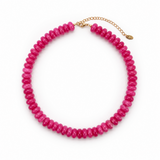 A chunky beaded necklace made of faceted hot pink beads, completed with a gold-tone chain extender and clasp, shown on a plain white background.