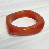 Chunky sculpted square bangle with a modern retro design, featuring a glossy finish and bold geometric shape.