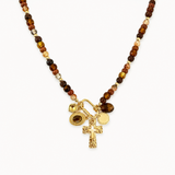 Necklace with brown beaded chain and gold charms on a white background