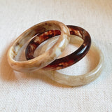 Set of three bold resin bangles in natural earth tones, featuring a mix of marbled and solid finishes for a stylish stacked look.