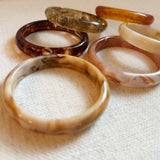 Set of three bold resin bangles in natural earth tones, featuring a mix of marbled and solid finishes for a stylish stacked look.