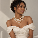 Bride-style model in an off-the-shoulder ivory gown wearing the Noble Pearl 3-Piece Necklace Set layered for a wedding look