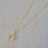 Gold-tone necklace featuring an oval-cut pendant with a sparkling crystal center, offering a refined and elegant touch.