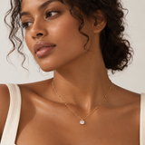 a woman with wavy hair wearing an oval cut diamond looking pendant necklace with gold ball chain.
