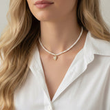 Refined pearl necklace featuring a small gold heart pendant adorned with sparkling crystals. The minimalist yet elegant design offers a timeless touch perfect for layering or wearing on its own.