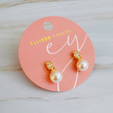 Gold-plated stud earrings featuring a luminous round pearl paired with a vertically set baguette-cut cubic zirconia, offering a sophisticated mix of classic and modern sparkle.