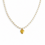 Necklace with gold heart pendant and white beads on a white background