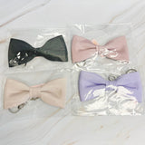 Four bow-shaped keychains in different colors on a light surface.