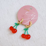 Playful cherry-themed earrings featuring vibrant red cherry charms with green stems, adding a fun and fruity touch to any outfit.
