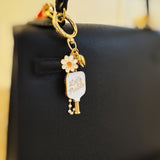 Decorative bag charm featuring a pickleball paddle- with “Let’s Pickle” text—plus a daisy flower and gold-tone accents, perfect for adding a playful touch to any bag.