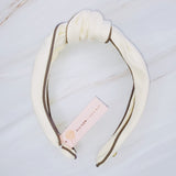 Structured preppy headband featuring a contrasting piped border detail, adding a polished and classic touch to any hairstyle.