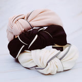 Structured preppy headband featuring a contrasting piped border detail, adding a polished and classic touch to any hairstyle.