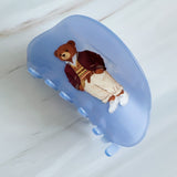 Preppy-inspired bear hair claw clips featuring fashionable teddy bear dressed in vintage collegiate outfits. Each clip showcases a different bear character on a pastel background, adding a playful yet polished touch to any hairstyle.