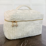 Quilted velvet vanity bag with top handle and zipper closure, available in creamy velvet and vintage moss color variants