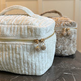 Quilted velvet vanity bag with top handle and zipper closure, available in creamy velvet and vintage moss color variants