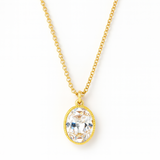 Close-up of a woman wearing a delicate gold chain necklace featuring a vintage-style oval pendant with a radiant engraved pattern and sparkling center stone, resting elegantly on her collarbone.
