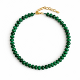 A collection of polished gemstone bead necklaces in various colors, including deep blue, green, brown, pink, and cream. Each necklace features smooth, rounded beads with a glossy finish, offering a timeless and versatile accessory look.