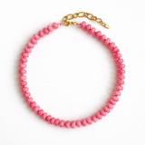 A collection of polished gemstone bead necklaces in various colors, including deep blue, green, brown, pink, and cream. Each necklace features smooth, rounded beads with a glossy finish, offering a timeless and versatile accessory look.