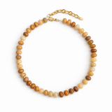 A collection of polished gemstone bead necklaces in various colors, including deep blue, green, brown, pink, and cream. Each necklace features smooth, rounded beads with a glossy finish, offering a timeless and versatile accessory look.