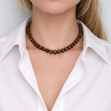 A collection of polished gemstone bead necklaces in various colors, including deep blue, green, brown, pink, and cream. Each necklace features smooth, rounded beads with a glossy finish, offering a timeless and versatile accessory look.
