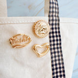 Gold-tone brooch pin with the word “Mother” in elegant retro script, framed by an oval border for a classic vintage look.