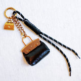 Glamorous bag charm featuring a mini purse design with gold-tone accents and playful details—perfect for adding a touch of sass and luxe to any handbag or tote.