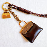 Glamorous bag charm featuring a mini purse design with gold-tone accents and playful details—perfect for adding a touch of sass and luxe to any handbag or tote.