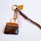 Glamorous bag charm featuring a mini purse design with gold-tone accents and playful details—perfect for adding a touch of sass and luxe to any handbag or tote.