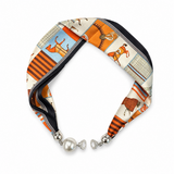 A silk scarf necklace with a vintage-inspired print featuring orange, beige, and blue motifs, finished with silver-toned hardware and a white pearl accent.