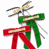 Three ribbon hair clips in red, green, and gold on a white background