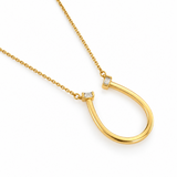 Angled close-up of the polished gold Sculpted U pendant showing bezel-set baguette cubic zirconia stones