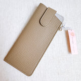 Sleek glass case bag charm with a button-up closure and strap attachment, offering a stylish and convenient way to carry your glasses on the go.