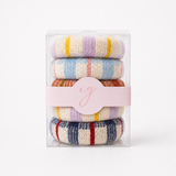 A set of four stacked knit hair scrunchies in a clear plastic package with a light pink paper band. The scrunchies feature various stripe patterns in pastel and bright colors including purple, yellow, blue, orange, red, and navy on a cream base.