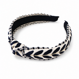 A knotted fabric headband featuring a navy blue and cream leaf pattern, displayed on a clean white background.