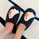 Black cozy slippers featuring a white ghost with a pumpkin detail, offering a playful and spooky seasonal touch.