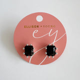A pair of black gemstone stud earrings featuring faceted rectangular stones set in silver-toned prong settings, offering a bold and refined statement look.