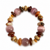 A beaded stretch bracelet featuring polished pinkish-purple cat's eye beads, dark brown and reddish-brown stones, orange agate beads, and natural gold-sparkedled beads, arranged in a circular shape on a white background.