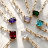 Gold necklaces with colorful gemstones on a marble surface