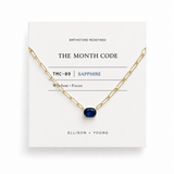 Gold chain necklace with a blue gemstone on a 'The Month Code' card.